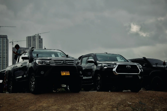 Several black suvs parked under a cloudy sky.
